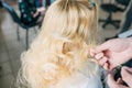 Back view of hairdresser working with long blonde hair of her customer in barber shop Royalty Free Stock Photo