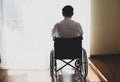 Back view of handicapped Man sitting on wheelchair in front of a large panoramic window in hospital,He is Lonely sad and deep in Royalty Free Stock Photo