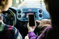 Back view of hands of young couple driving using navigation on mobile phone