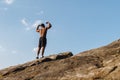 Back view of handsome african american bodybuilder posing on rock against the blue cloudy sky Royalty Free Stock Photo