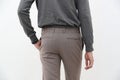 Back view of a handsome man in gray turtleneck shirt and long trousers on white background