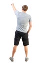 Back view of handsome man in t-shirt and shorts pointing