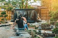 Back view of Happiness Asian family feeding koi or fancy carp in small pond with beautiful garden decorated in Japanese style. Royalty Free Stock Photo