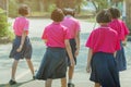 Back view of happiness primary girl students in pink shirt and blue skirt walk to classrooms