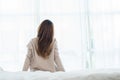 Back view of happy beautiful young Asian woman waking up in morning, sitting on bed, stretching in cozy bedroom. Royalty Free Stock Photo