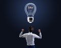 Back view of businessman with creative glass idea light bulb on dark background. Inspiration and genius concept