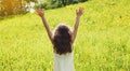 Back view happy little girl child having fun raising her hands up in summer day Royalty Free Stock Photo