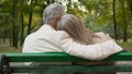 Back view happy lovely gray haired senior married couple sitting bench talk discuss hugging city park outside. Romantic Royalty Free Stock Photo