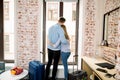 Back view of happy loving couple in hotel room, hugging and standing on window background. Family on vacation, honeymoon Royalty Free Stock Photo