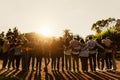 Back view of happy multigenerational people having fun in a public park during sunset time