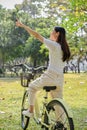 Back view, Happy Asian woman enjoys looking at the view while cycling in the public park Royalty Free Stock Photo