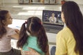 Mom and daughters sitting at laptop and having class with online English teacher Royalty Free Stock Photo