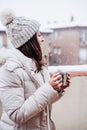 Back view of happy woman on terrace at home enjoying cup of hot coffee, neighborhood background. Snow in the city Royalty Free Stock Photo