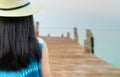 Back view of happy young Asian woman in casual style fashion and straw hat relax and enjoy holiday at tropical paradise beach. Royalty Free Stock Photo