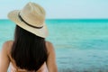 Back view of happy young Asian woman in pink swimsuit and straw hat relax and enjoy holiday at tropical paradise beach at sunset. Royalty Free Stock Photo