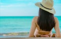 Back view of happy young Asian woman in pink swimsuit and straw hat relax and enjoy holiday at tropical paradise beach at sunset. Royalty Free Stock Photo