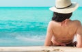 Back view of happy young Asian woman in pink swimsuit and straw hat relax and enjoy holiday at tropical paradise beach at sunset. Royalty Free Stock Photo