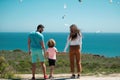 Back view of happy young family walking on beach. Child with parents holding hands. Full length freedom poeple. Royalty Free Stock Photo