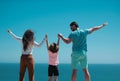 Back view of happy young family walking on beach. Child with parents holding hands. Full length poeple. Royalty Free Stock Photo