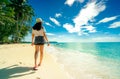 Back view of happy young woman in casual style fashion and straw hat wear sandals walking at sand beach. Relaxing and enjoy Royalty Free Stock Photo