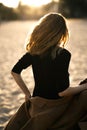 Back view of happy young woman standing on sand on the beach at sunset. Royalty Free Stock Photo