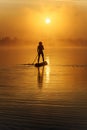 Back view of healthy man rowing with paddle board on lake