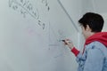 Back view of high school student solving math problem on whiteboard in classroom. Royalty Free Stock Photo