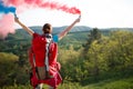 Back view of hiker girl with backpack while sends smoke signal