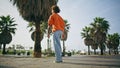 Back view hipster walking city square summer day. Guy going near tropical palms Royalty Free Stock Photo