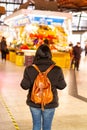 Back view of a Hispanic girl with a brown backpack at the Boqueria Market in Barcelona, Spain