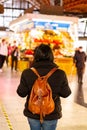 Back view of a Hispanic girl with a brown backpack at the Boqueria Market in Barcelona, Spain