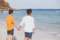 Back view homosexual young asian couple standing together on beach in summer, asia gay holding hands going sea for leisure Royalty Free Stock Photo