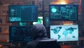 Back view of hooded cyber terrorist using super computer