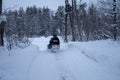 Back view of human driving snowmobile in forest