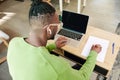 Back view image of young african man in glasses and earphones working, studying remotely at home, looking on laptop Royalty Free Stock Photo