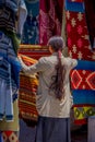 Back view of indigenous woman wearing andean traditional clothing and selling some products in the street market in the