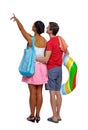 Back view of a an international pointing couple with an inflatable circle and beach accessories