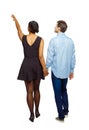 Back view of interracial going couple who points somewhere Royalty Free Stock Photo