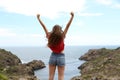 Back view of a joyful teen raising arms