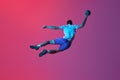 Back view. In a jump. Young man, professional handball player training, playing isolated over gradient pink background