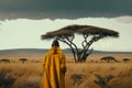 Back view of kenya man in tradishional yellow clothes enjoying nature view of National park Maasai Mara.