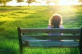 Back view of kid sitting on the bench at sunset in the park Royalty Free Stock Photo