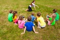 Back view of kids sitting on a grass playing charades Royalty Free Stock Photo