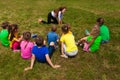 Back view of kids sitting on a grass playing charades Royalty Free Stock Photo