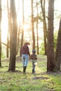 Back view likable bearded grandpa in forest going fishing together with his 10-aged grandson and talking about fishing.