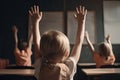 Back view of little boy raising hands up while sitting in classroom at school, Little students full rear view raising their hands Royalty Free Stock Photo