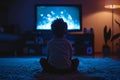 Back view of a little boy sitting in front of tv. Child watching television in dark living room. Films and movies for family. Royalty Free Stock Photo