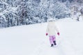 back view of little child in warm clothes walking on snow in winter park Royalty Free Stock Photo