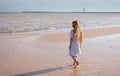 Back view of little girl with long hair in white dress walking on tropical beach vacation Royalty Free Stock Photo