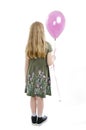 Back view of little girl looking at wall holding pink balloon. Rear view.